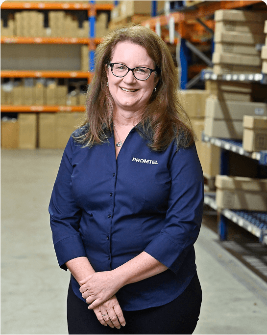 Melissa from Promtel standing and smiling in front of the warehouse shelf